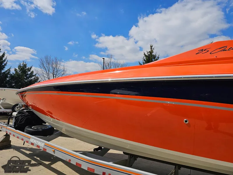 Slide: The Image of 2007 Baja 35 Outlaw boat with vibrant orange hull on a trailer under blue sky. - 23