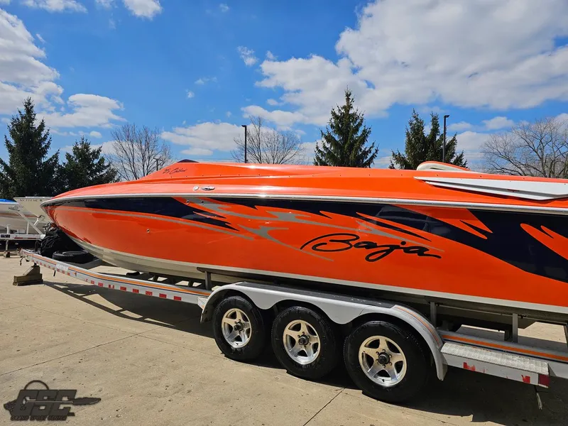 Slide: The Image of 2007 Baja 35 Outlaw speedboat on trailer, vibrant orange with bold graphics, under blue sky. - 27