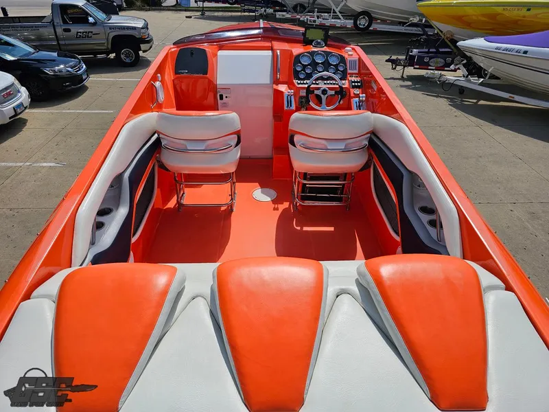 Slide: The Image of 2007 Baja 35 Outlaw boat interior with vibrant orange and white seating, parked outdoors. - 49