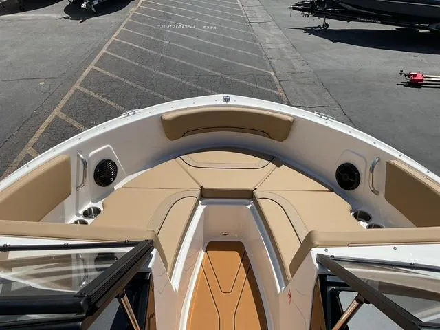 Slide: The Image of 2025 Bayliner V20i boat interior with tan seating and speakers, docked on pavement. - 9