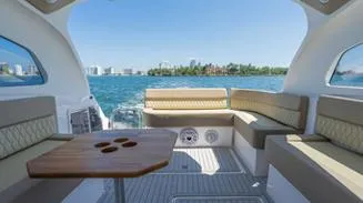 Slide: The Image of 2025 Hanover 375 Inboard boat interior with seating and table, overlooking a scenic water view. - 9