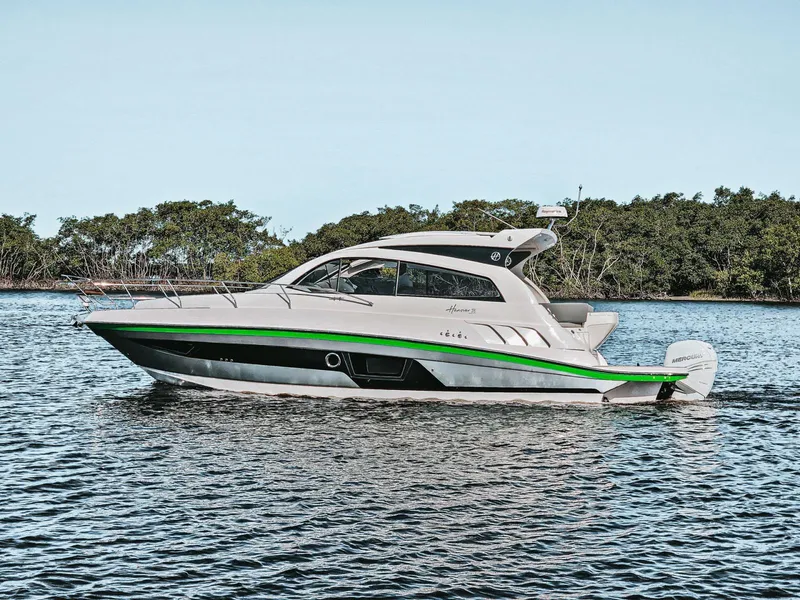 The Image of 2025 Hanover 375 Outboard boat cruising on a calm lake with lush greenery. - 0