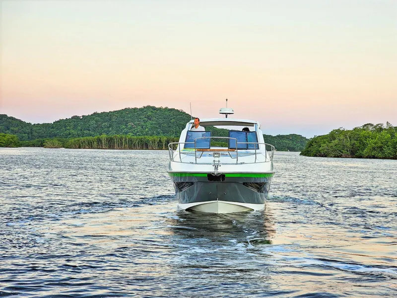 Slide: The Image of 2025 Hanover 375 Outboard cruising on serene water with lush green hills in the background. - 2