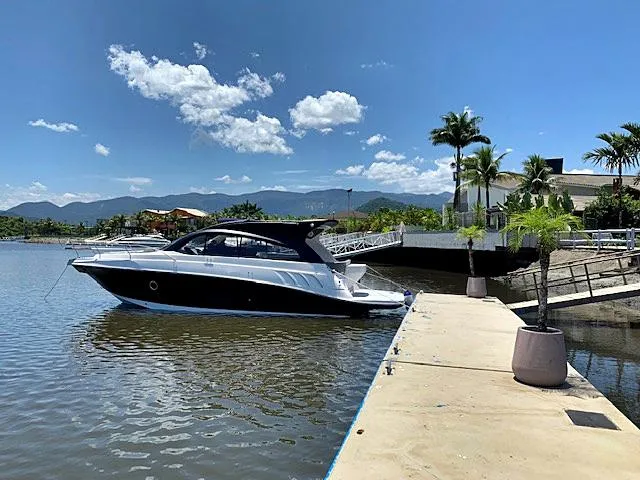 Slide: The Image of 2025 Hanover 355 Outboard boat docked by a scenic waterfront with mountains and palm trees. - 1
