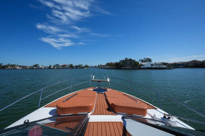 Slide: The Image of 2025 Hanover 355 Outboard cruising on a sunny day, showcasing luxury deck and waterfront view. - 4
