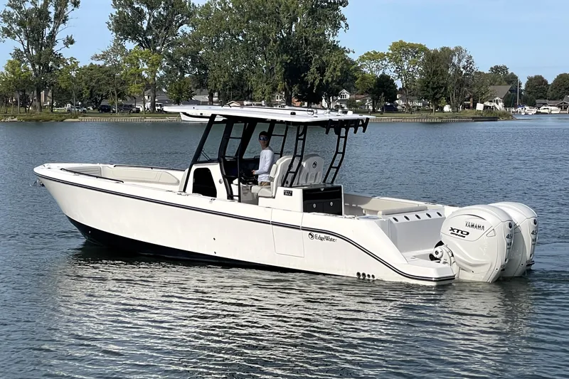 The Image of 2025 Edgewater 340CC boat on a calm lake with trees in the background. - 0
