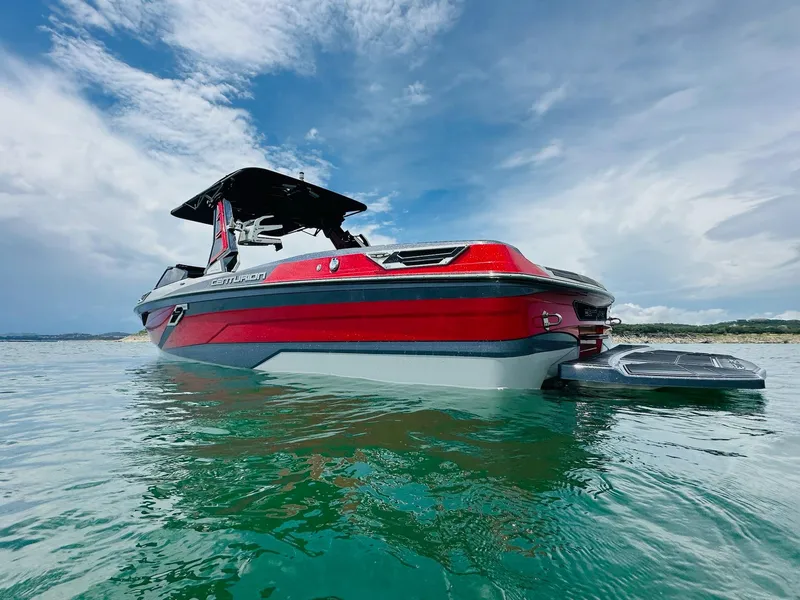 Slide: The Image of 2021 Centurion Ri265 boat on water, red and gray design, under a cloudy sky. - 1