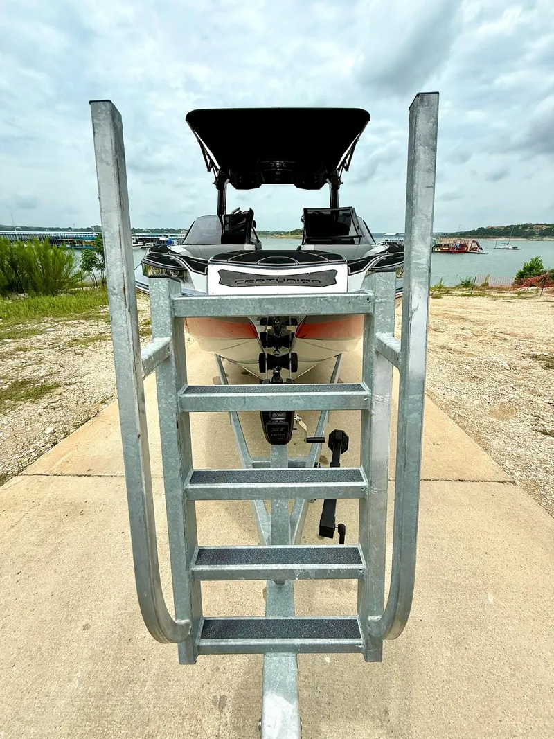 Slide: The Image of 2021 Centurion Ri265 boat on trailer with metal steps, near a lake. - 10