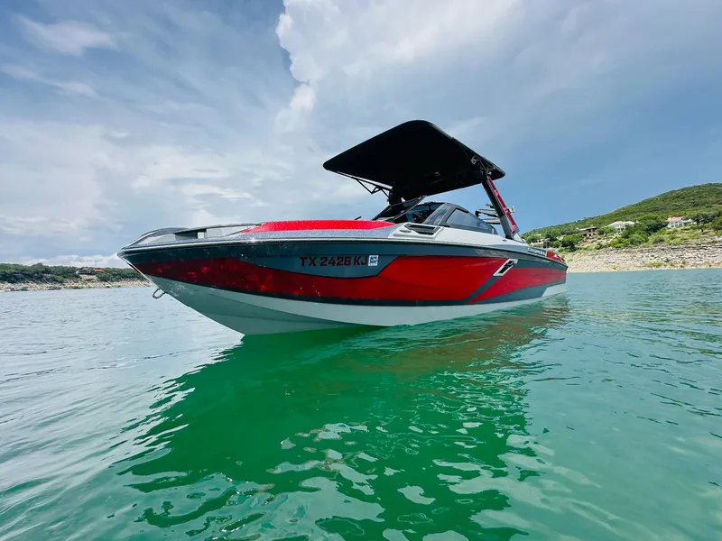 Slide: The Image of 2021 Centurion Ri265 boat on clear water under a partly cloudy sky. - 2