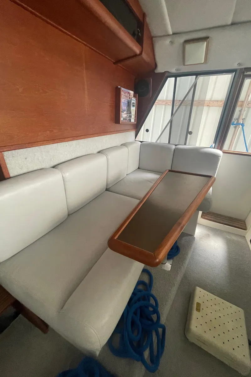 Slide: The Image of Interior of 1988 Bayliner 4588 yacht with white seating and wooden table. - 12