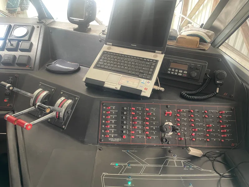 Slide: The Image of Control panel of a 1988 Bayliner 4588 yacht with levers, switches, and a laptop. - 14