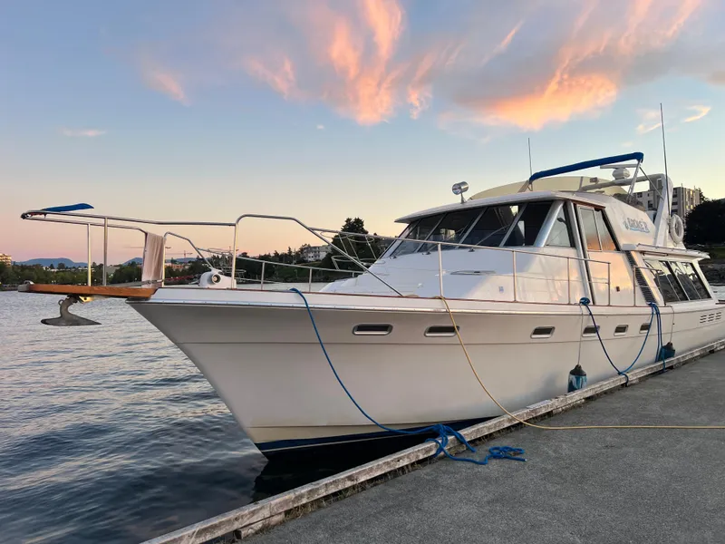 Slide: The Image of 1988 Bayliner 4588 yacht docked at sunset with scenic sky and water backdrop. - 2