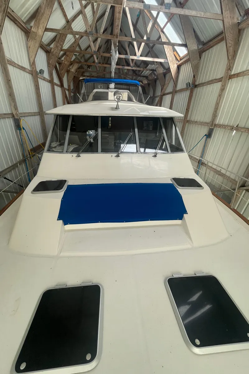 Slide: The Image of 1988 Bayliner 4588 yacht in a wooden boathouse, showcasing its sleek design and structure. - 27