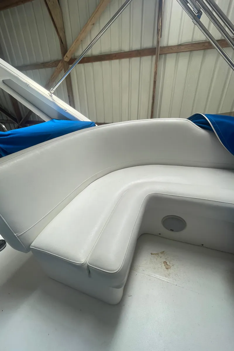 Slide: The Image of 1988 Bayliner 4588 boat interior with white cushioned seating and blue cover. - 32