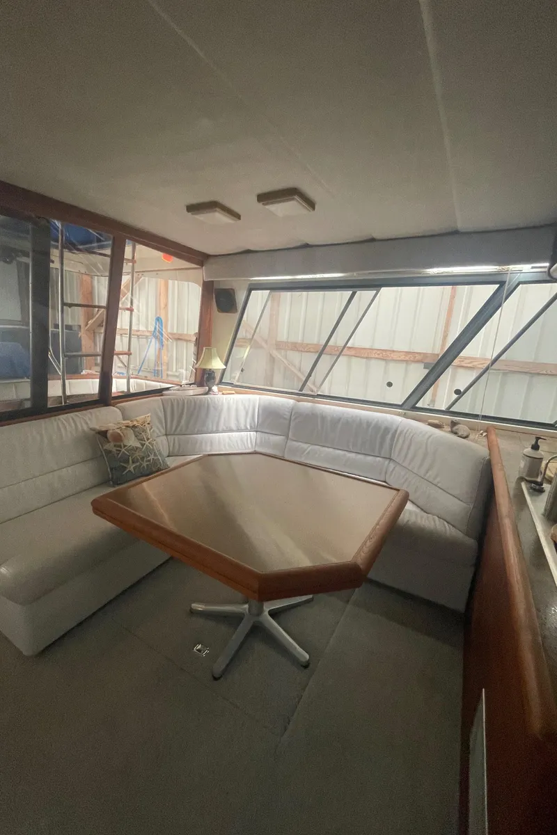 Slide: The Image of 1988 Bayliner 4588 yacht interior with white leather seating and wooden table. - 7