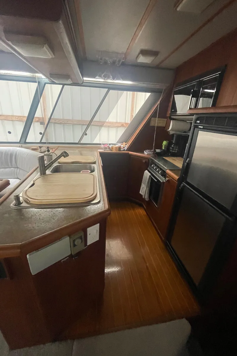 Slide: The Image of 1988 Bayliner 4588 yacht kitchen with wood flooring, modern appliances, and large windows. - 8