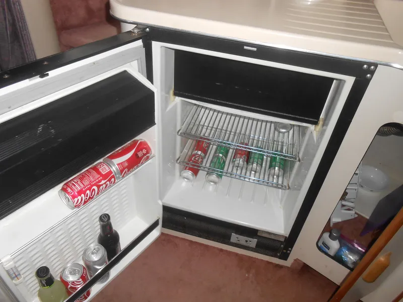 Slide: The Image of Mini fridge stocked with beverages inside a 1990 Sea Ray 350 Sundancer Coupe boat. - 11