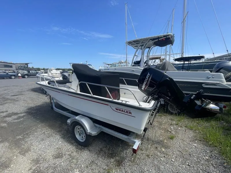 Slide: The Image of 2024 Boston Whaler 150 Montauk boat on trailer, parked outdoors under clear sky. - 3
