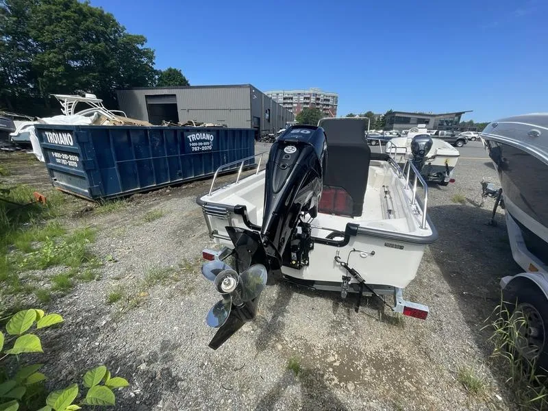 Slide: The Image of 2024 Boston Whaler 150 Montauk boat with outboard motor, parked outdoors on gravel. - 4