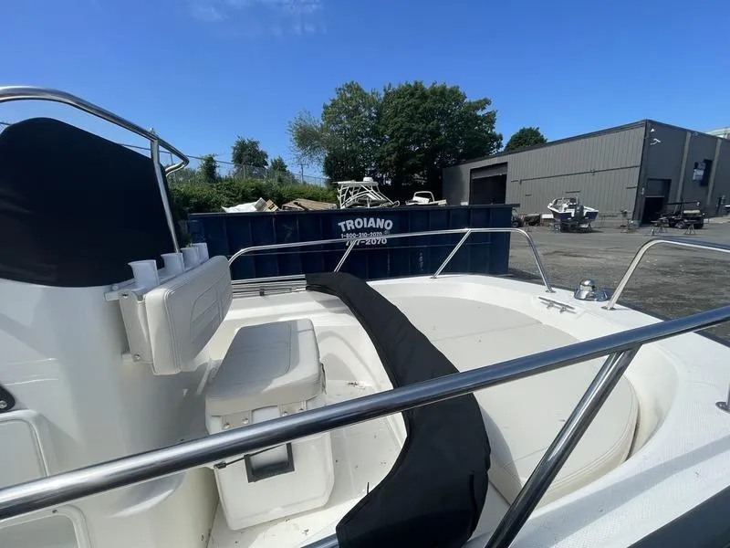 Slide: The Image of 2024 Boston Whaler 150 Montauk boat interior with seating, docked outdoors. - 5