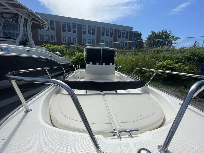 Slide: The Image of 2024 Boston Whaler 150 Montauk boat docked outdoors under a clear blue sky. - 9