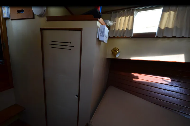 Slide: The Image of 1977 Grand Banks GB 32 cabin interior with bed, window, and wooden paneling. - 12