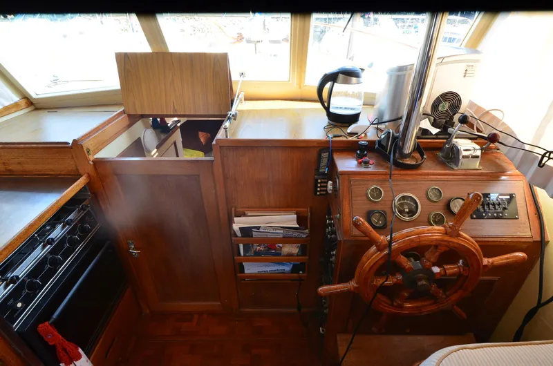 Slide: The Image of 1977 Grand Banks GB 32 helm with wooden wheel, gauges, and kitchen area. - 20