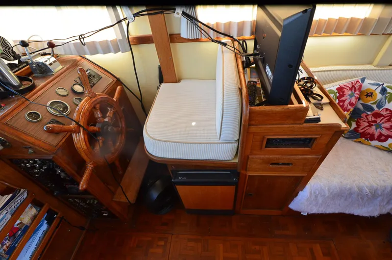 Slide: The Image of 1977 Grand Banks GB 32 helm with wooden wheel, gauges, and cozy seating area. - 21