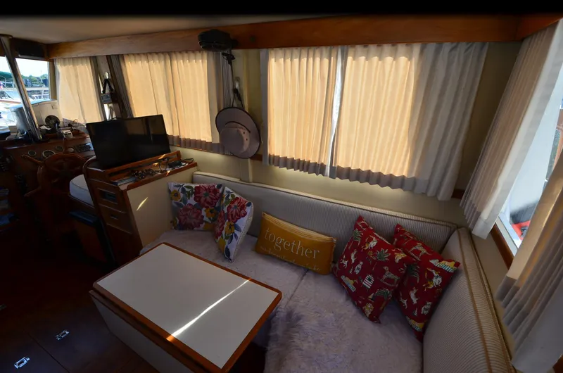 Slide: The Image of 1977 Grand Banks GB 32 yacht interior with cozy seating, floral pillows, and a small TV. - 22