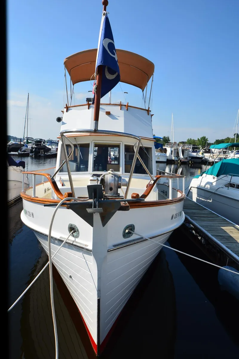 Slide: The Image of 1977 Grand Banks GB 32 boat docked at marina, front view with blue flag. - 28