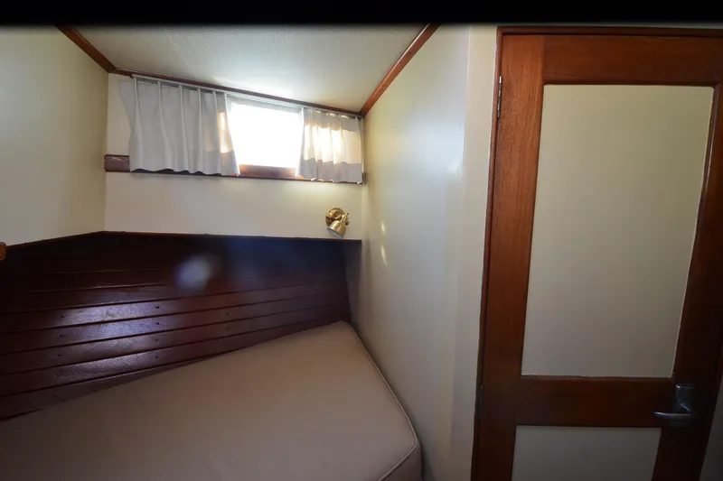 Slide: The Image of 1977 Grand Banks GB 32 cabin interior with wooden paneling and small window. - 35