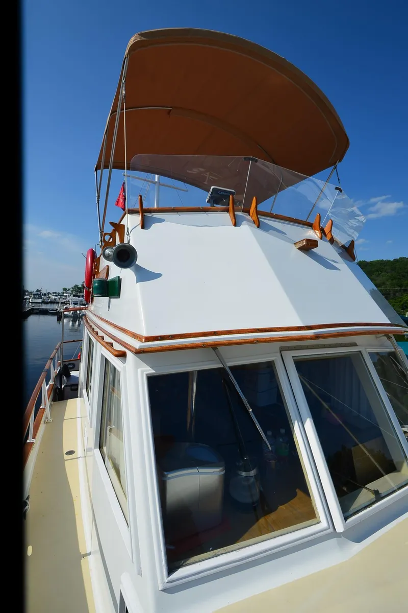 Slide: The Image of 1977 Grand Banks GB 32 boat with canopy, docked under clear blue sky. - 38