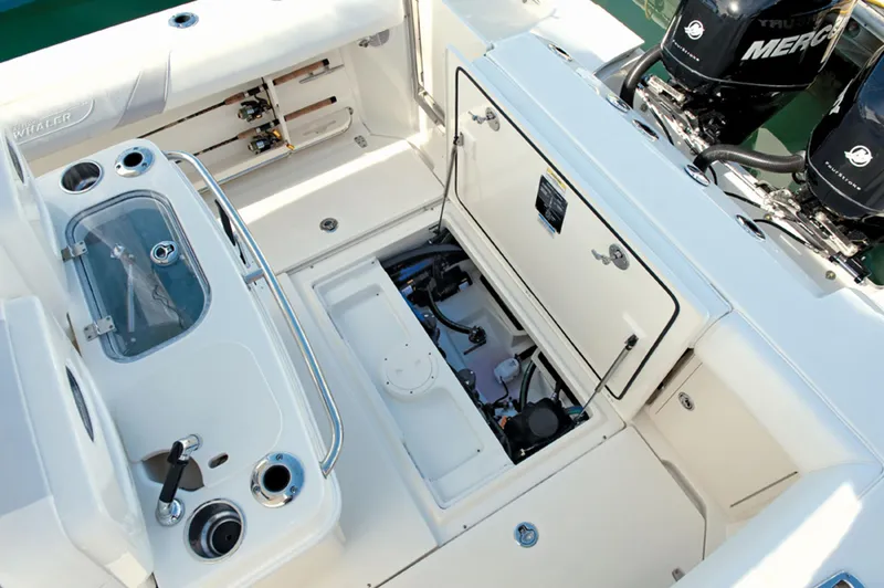 Slide: The Image of 2014 Boston Whaler 250 Outrage boat interior with open storage compartments and twin Mercury engines. - 14