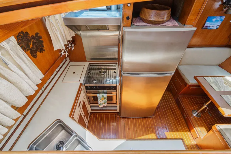 Slide: The Image of 1986 Offshore Yachts 48 Yachtfisher galley with stainless steel appliances and wooden cabinetry. - 13