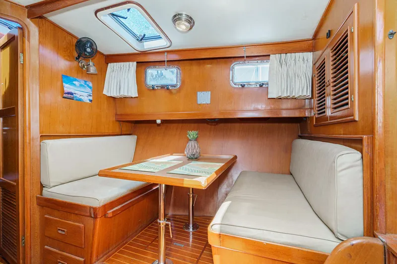 Slide: The Image of 1986 Offshore Yachts 48 Yachtfisher interior with cozy dining area and wooden finishes. - 15