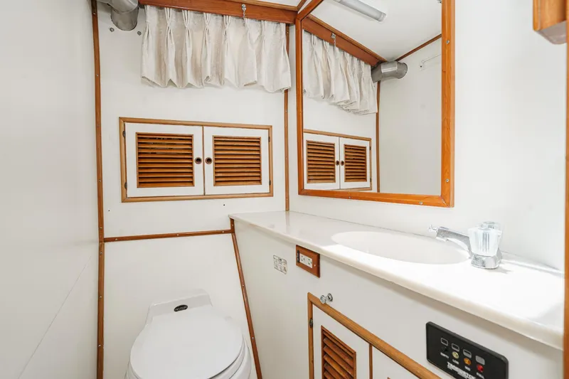 Slide: The Image of 1986 Offshore Yachts 48 Yachtfisher bathroom with wooden accents and white fixtures. - 29