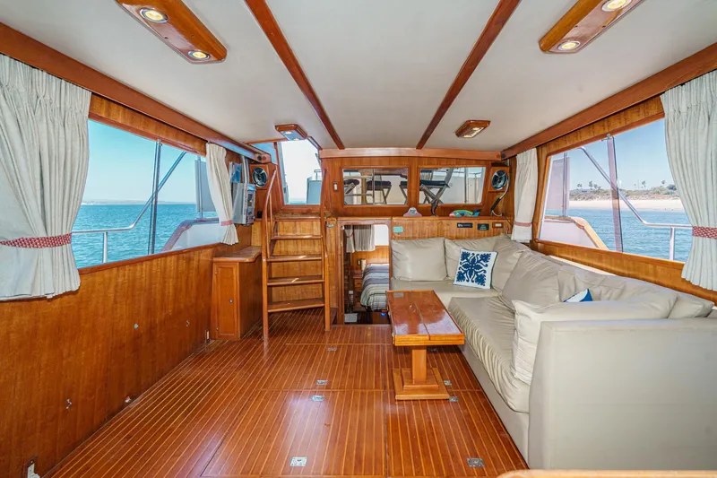 Slide: The Image of 1986 Offshore Yachts 48 Yachtfisher interior with wood paneling, sofa, and ocean view. - 9