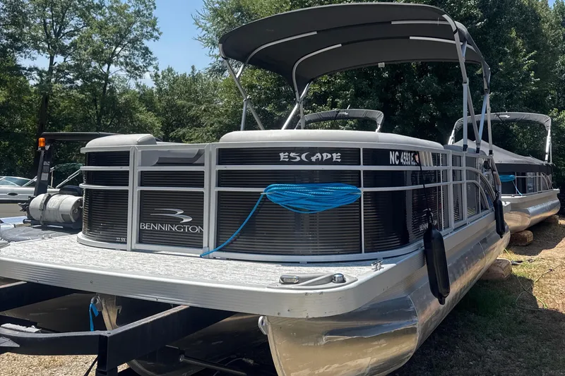 Slide: The Image of 2023 Bennington 22SX Swingback pontoon boat with canopy, parked outdoors. - 0
