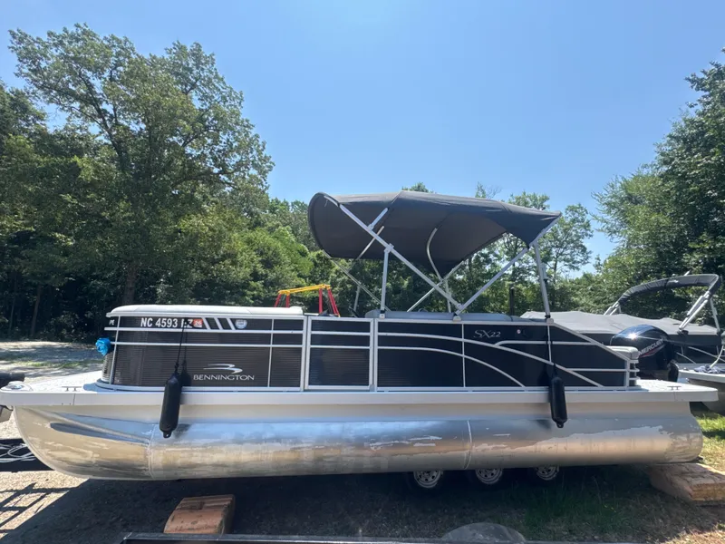 Slide: The Image of 2023 Bennington 22SX Swingback pontoon boat with canopy, parked outdoors. - 1