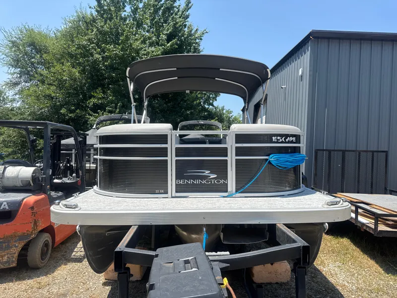 Slide: The Image of 2023 Bennington 22SX Swingback pontoon boat on trailer, parked outdoors. - 11