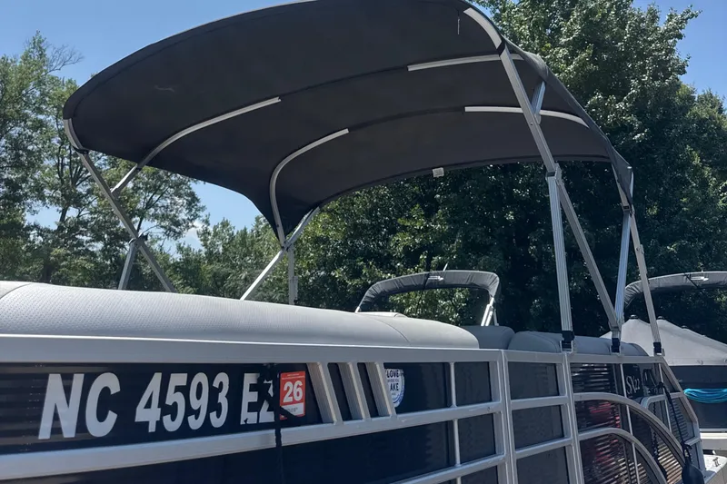 Slide: The Image of 2023 Bennington 22SX SWINGBACK pontoon boat with canopy, docked outdoors. - 4