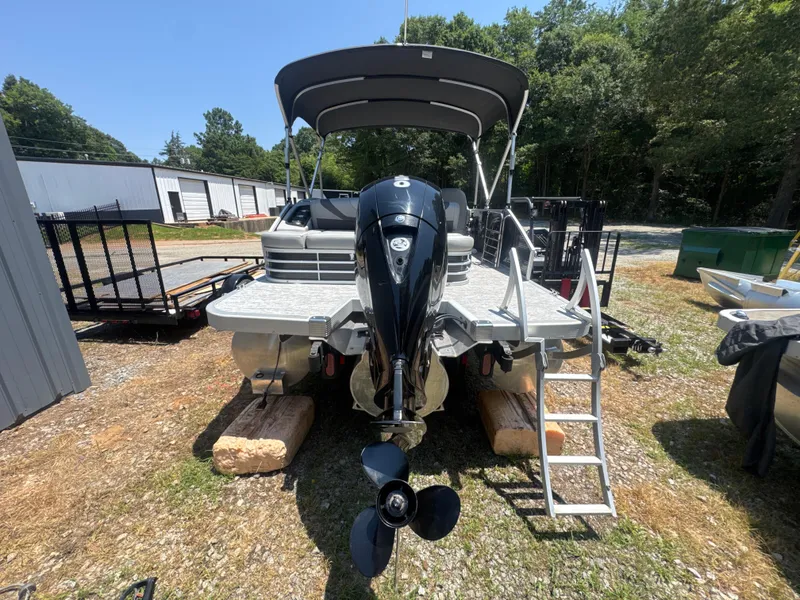 Slide: The Image of 2023 Bennington 22SX SWINGBACK pontoon boat with outboard motor and ladder, parked outdoors. - 6