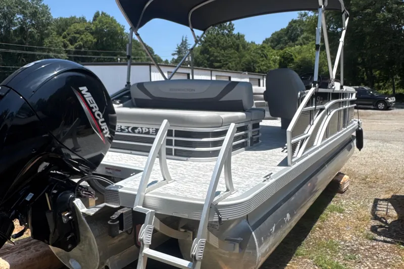 Slide: The Image of 2023 Bennington 22SX Swingback pontoon boat with Mercury engine, parked outdoors. - 7