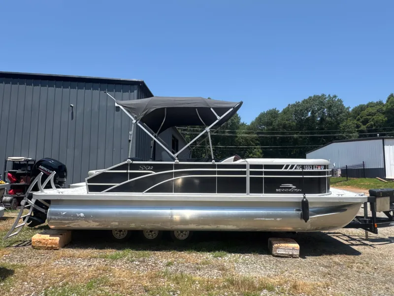 Slide: The Image of 2023 Bennington 22SX Swingback pontoon boat with canopy, parked outdoors. - 8