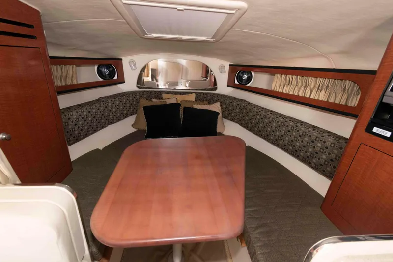 Slide: The Image of Interior cabin of 2005 Sea Ray 280 Sundancer with wood table and cushioned seating. - 14