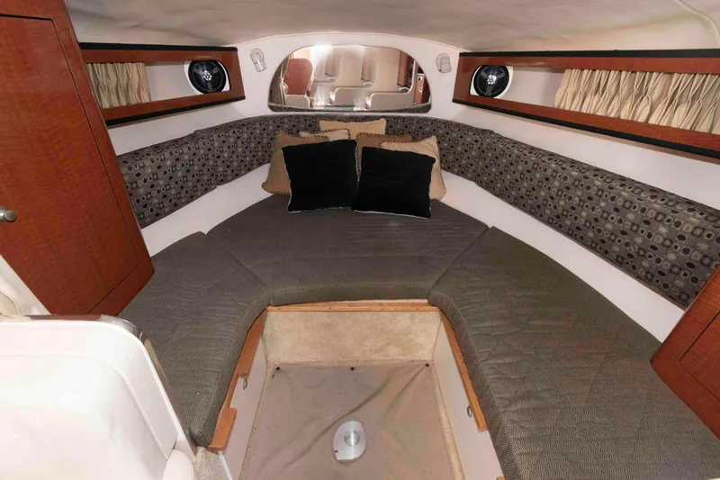 Slide: The Image of 2005 Sea Ray 280 Sundancer cabin interior with cushioned seating and wood accents. - 15