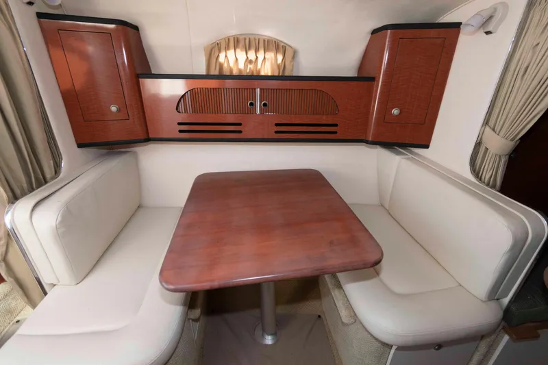 Slide: The Image of 2005 Sea Ray 280 Sundancer cabin interior with wooden table and cushioned seating. - 16
