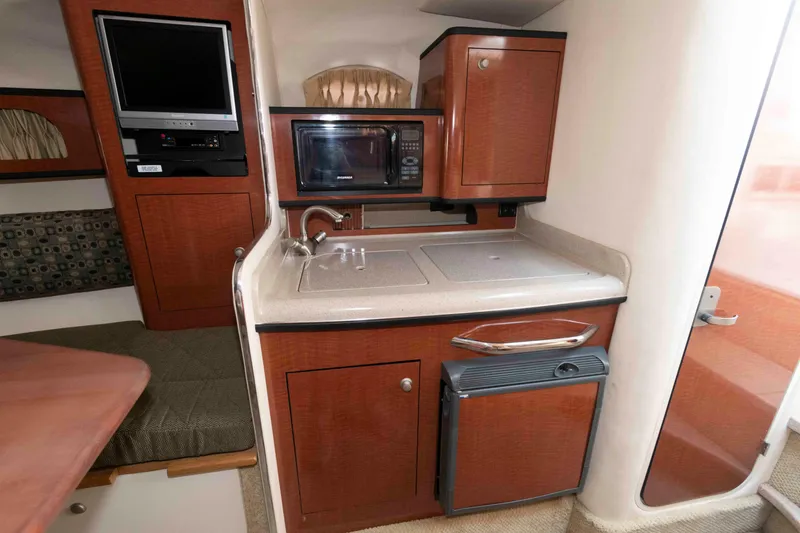 Slide: The Image of 2005 Sea Ray 280 Sundancer interior kitchen with microwave, sink, and compact fridge. - 17