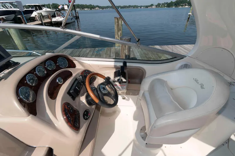 Slide: The Image of 2005 Sea Ray 280 Sundancer helm with gauges, steering wheel, and captain's chair by the dock. - 7