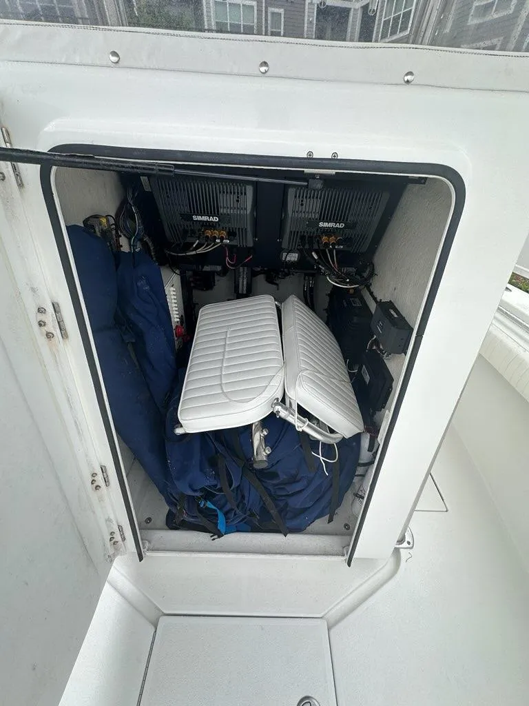 Slide: The Image of 2012 Onslow Bay 27 OE boat storage compartment with Simrad electronics and folded cushions. - 11